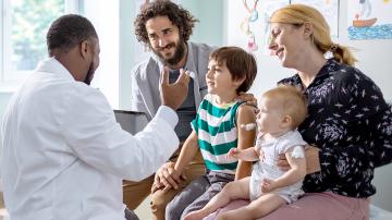 A Doctor sits with a family.