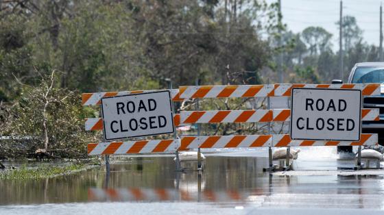 Road closure signs above standing water.