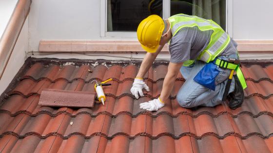 Construction worker fixing roof tiles.