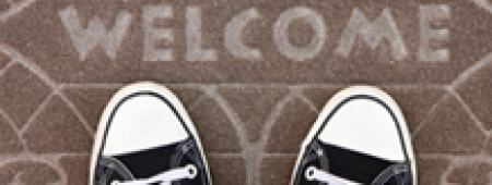 Shoes standing on Welcome sign on ground