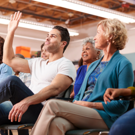 a group of people sitting in a classroom and raising their hands
