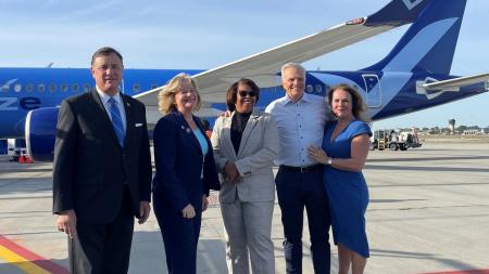 From left, Orange County Board of Supervisors Chairman Donald P. Wagner, Orange County District 5 Supervisor Katrina Foley, and Breeze Airways stand in front of Breeze Airways airplane on an airway strip of John Wayne Airport.