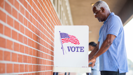 A senior black man casts his ballot on election day.