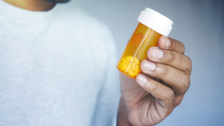 Young man holding medicine pill container.