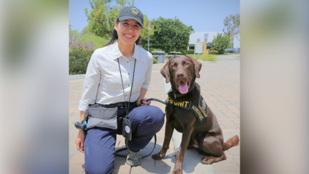 an orange county public works employee kneeling next to a brown inspection dog